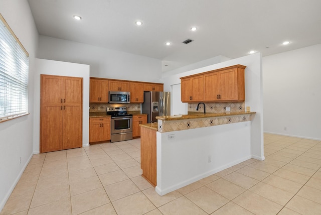 kitchen with kitchen peninsula, stainless steel appliances, decorative backsplash, and light tile patterned flooring