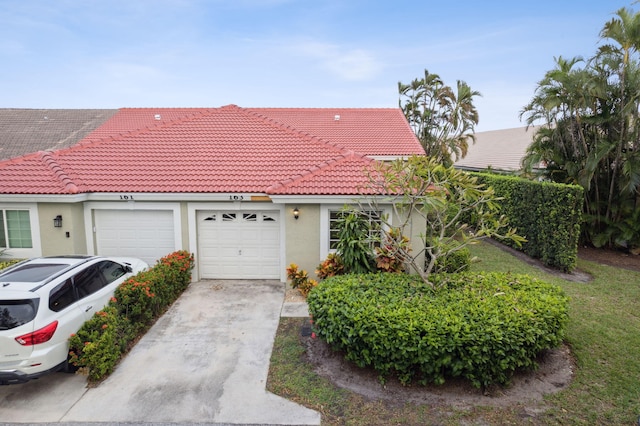 view of front of property featuring driveway, a tiled roof, an attached garage, and stucco siding