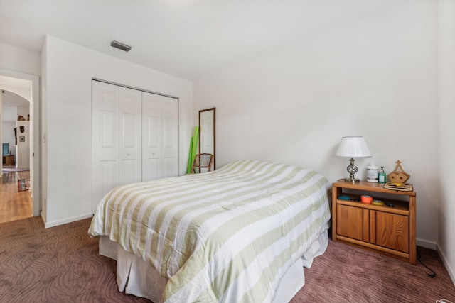 bedroom featuring dark colored carpet, a closet, visible vents, and baseboards