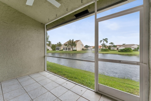 unfurnished sunroom featuring a residential view, a water view, and ceiling fan