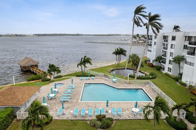 view of pool with a yard, a water view, and fence