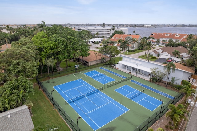 view of tennis court with a water view and fence