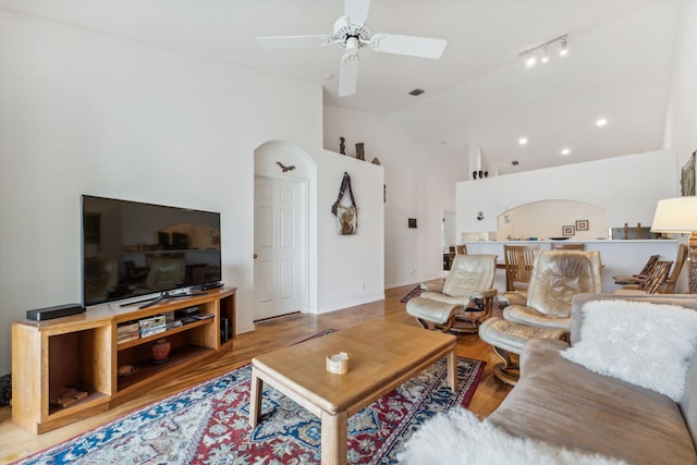 living room with a ceiling fan, arched walkways, visible vents, and wood finished floors