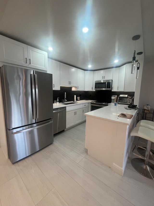 kitchen featuring kitchen peninsula, sink, white cabinets, appliances with stainless steel finishes, and tasteful backsplash