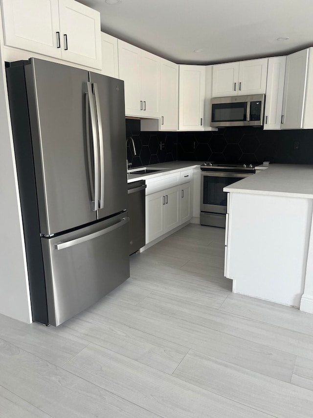 kitchen with backsplash, appliances with stainless steel finishes, sink, and white cabinets