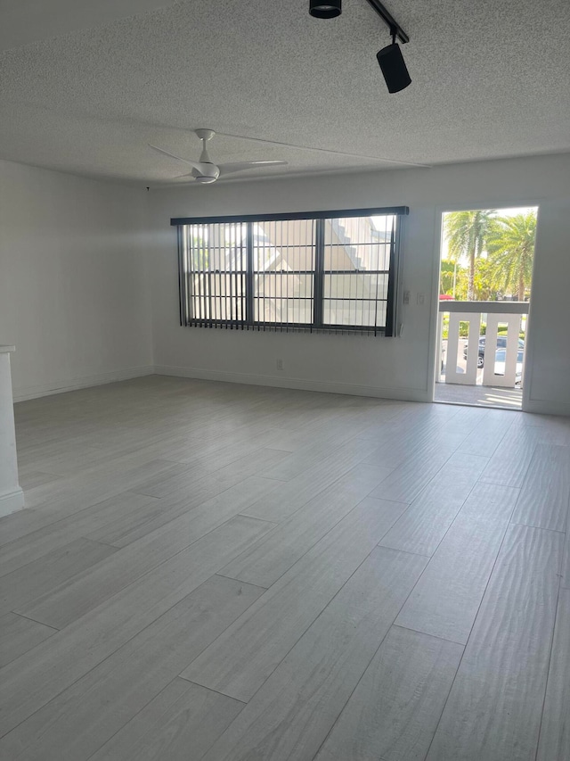 spare room with light hardwood / wood-style flooring, a textured ceiling, and a wealth of natural light