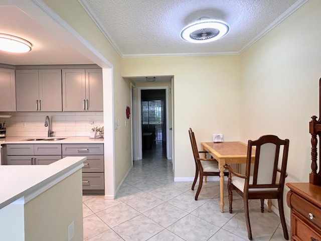 kitchen with gray cabinets, ornamental molding, sink, and a textured ceiling