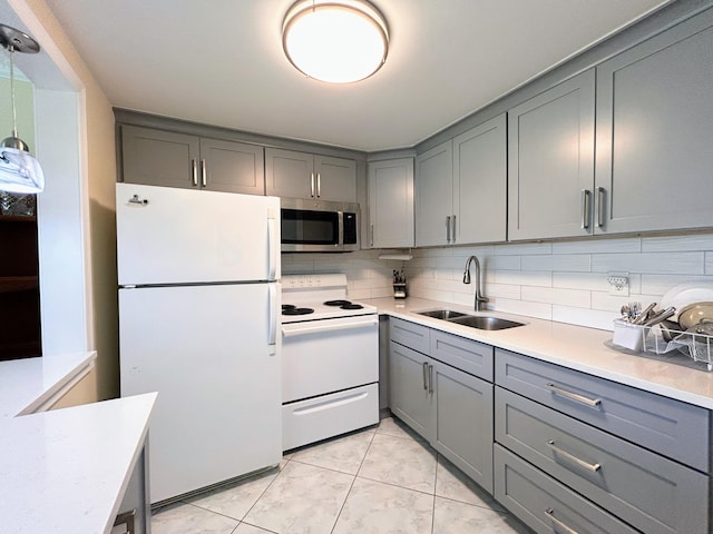 kitchen featuring white appliances, backsplash, sink, and gray cabinetry