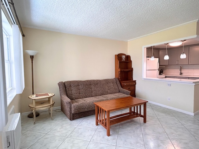 living room with light tile patterned floors, a textured ceiling, ornamental molding, and sink