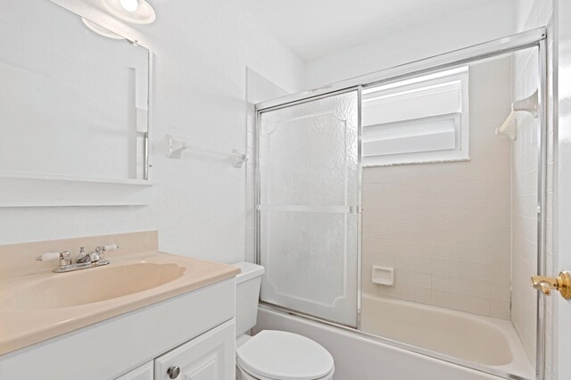 full bathroom featuring vanity, shower / bath combination with glass door, and toilet