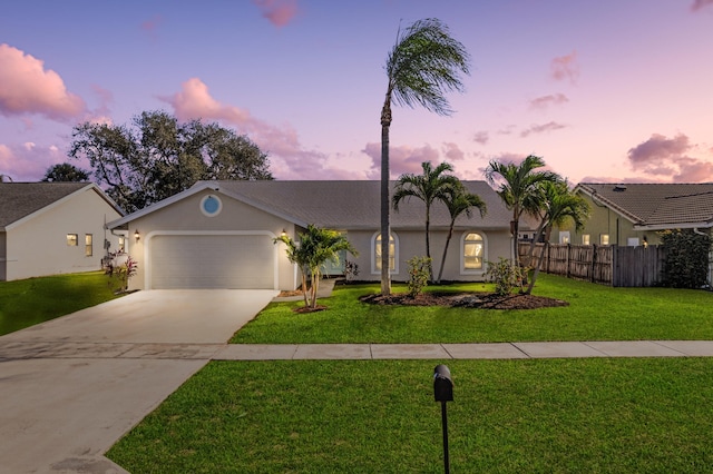 ranch-style home featuring a garage and a lawn