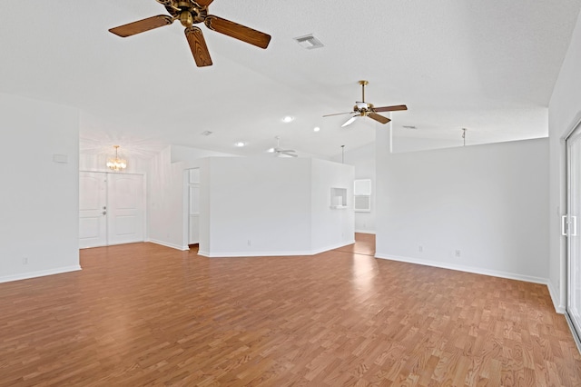 spare room with ceiling fan with notable chandelier, vaulted ceiling, a textured ceiling, and light wood-type flooring