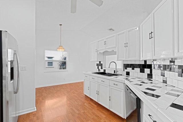 kitchen featuring sink, stainless steel fridge with ice dispenser, hanging light fixtures, dishwashing machine, and white cabinets