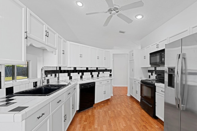 kitchen featuring sink, tile countertops, white cabinets, and black appliances