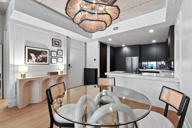 dining space with light hardwood / wood-style flooring and a chandelier