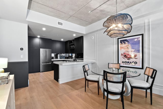 kitchen with high end fridge, light hardwood / wood-style flooring, hanging light fixtures, kitchen peninsula, and a notable chandelier