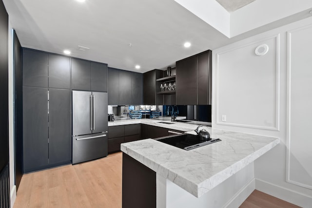 kitchen with light hardwood / wood-style flooring, kitchen peninsula, high quality fridge, and sink