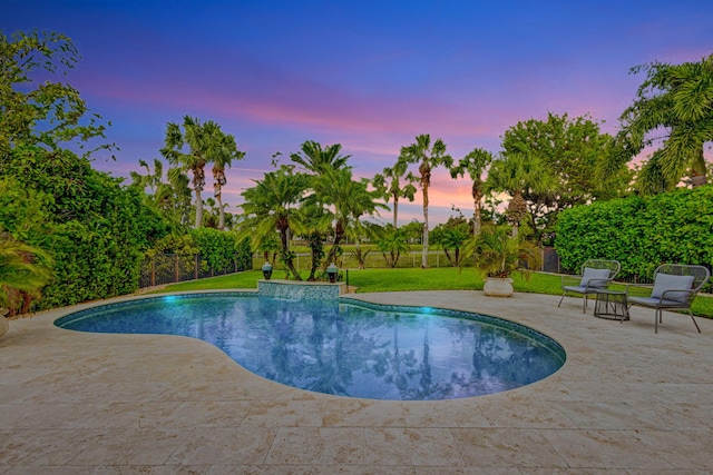 pool at dusk with a lawn and a patio