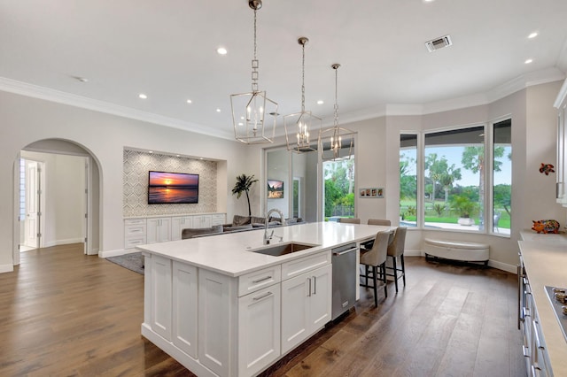 kitchen with pendant lighting, a center island with sink, sink, stainless steel dishwasher, and white cabinetry