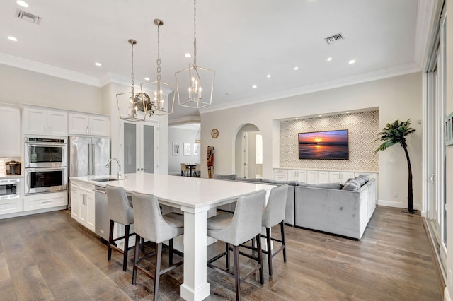 kitchen featuring a center island with sink, white cabinets, a breakfast bar area, and appliances with stainless steel finishes