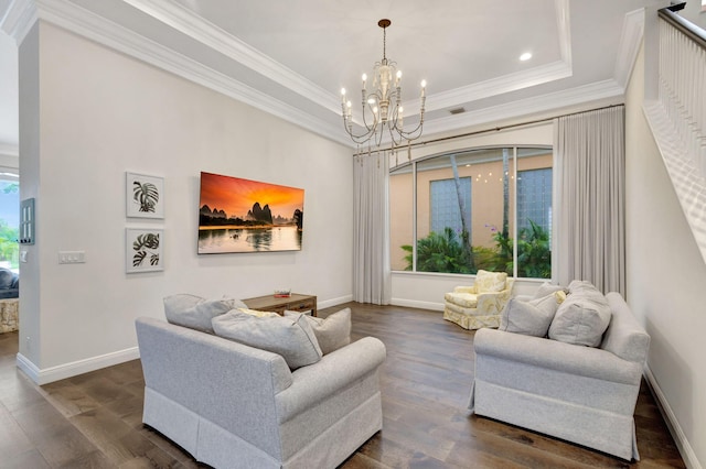 living room with a chandelier, ornamental molding, dark wood-type flooring, and a tray ceiling