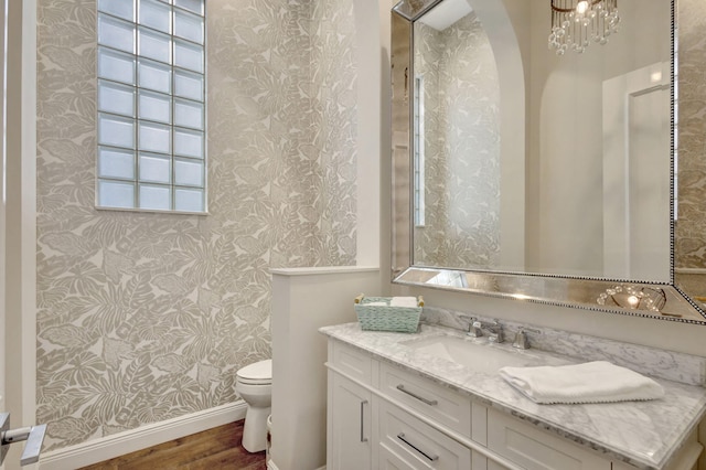 bathroom with hardwood / wood-style floors, vanity, a notable chandelier, and toilet