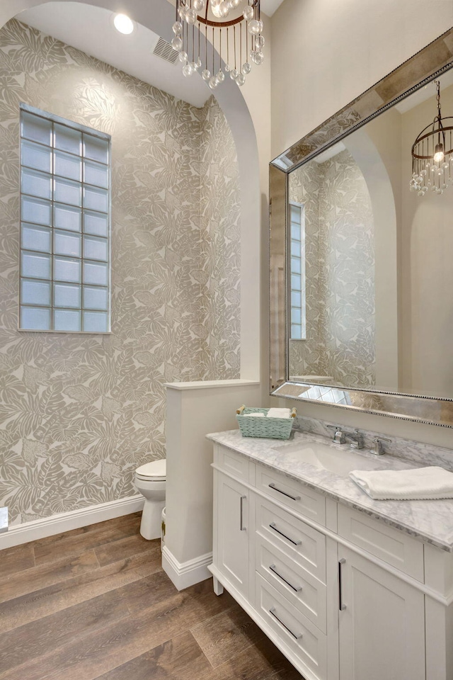 bathroom featuring toilet, hardwood / wood-style floors, vanity, and an inviting chandelier