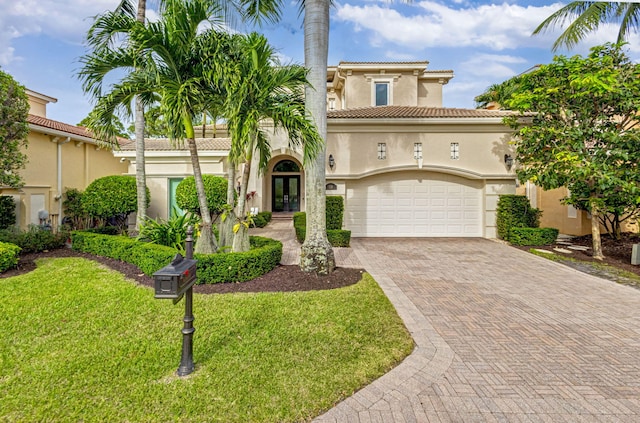 mediterranean / spanish-style house with a front yard, french doors, and a garage