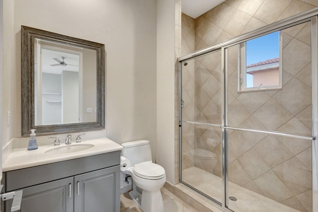 bathroom with ceiling fan, vanity, an enclosed shower, and toilet