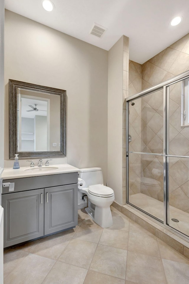 bathroom with tile patterned floors, a shower with door, vanity, and toilet