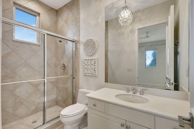 bathroom featuring a wealth of natural light, a shower with door, vanity, and toilet