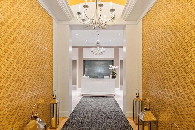 corridor with ornamental molding, a towering ceiling, and a chandelier