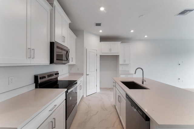 kitchen with stainless steel appliances, a kitchen island with sink, sink, and white cabinets