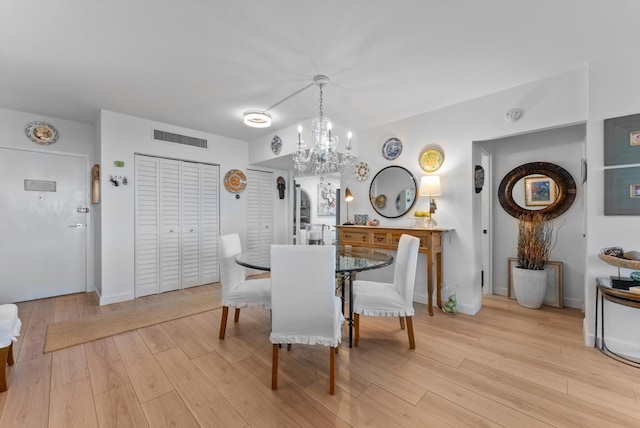 dining space featuring light wood-type flooring and a chandelier