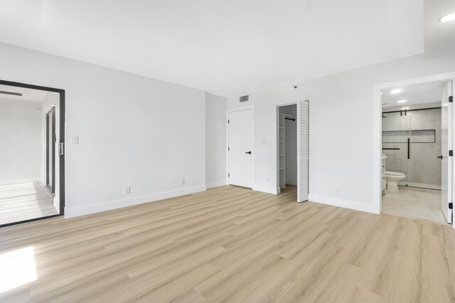 unfurnished bedroom with ensuite bath and light hardwood / wood-style floors