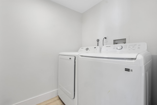 laundry room with washing machine and dryer and light wood-type flooring