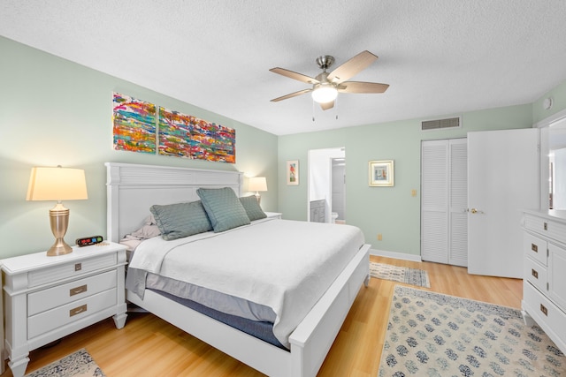 bedroom with a closet, light hardwood / wood-style floors, a textured ceiling, and ceiling fan