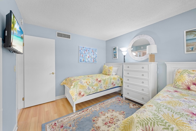 bedroom with a textured ceiling and hardwood / wood-style flooring