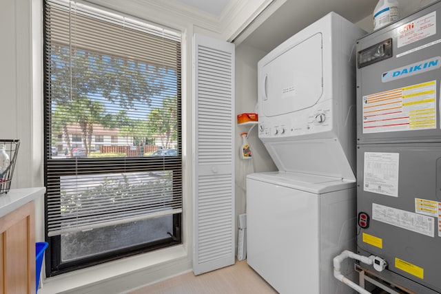 laundry area with stacked washer / drying machine, crown molding, and heating unit