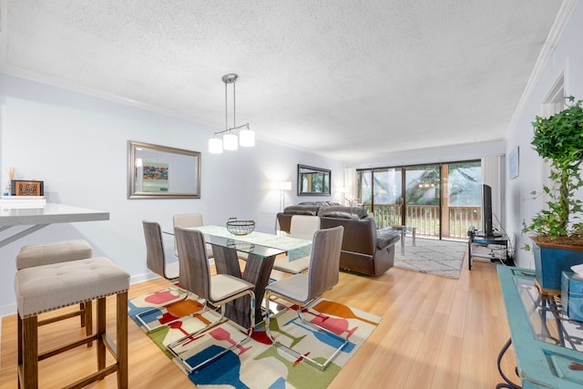 dining area with ornamental molding, a textured ceiling, and light wood-type flooring