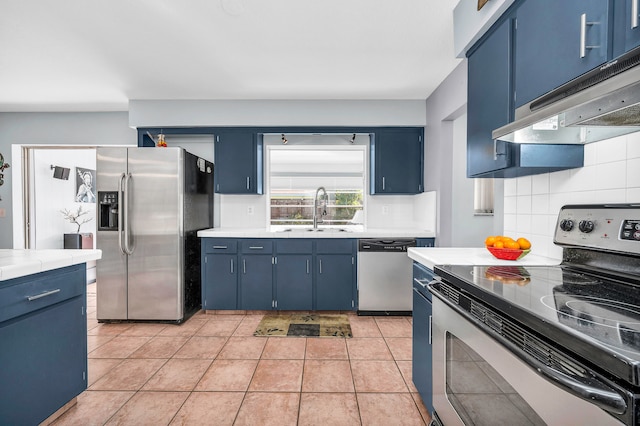 kitchen with blue cabinetry, sink, backsplash, light tile patterned floors, and appliances with stainless steel finishes