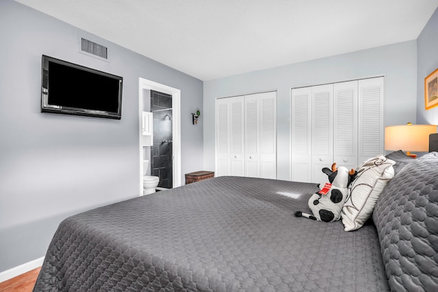 bedroom featuring two closets and ensuite bath