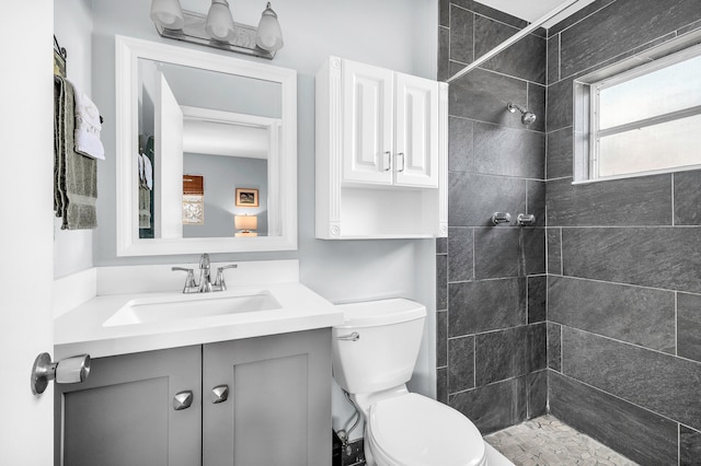 bathroom featuring a tile shower, vanity, and toilet