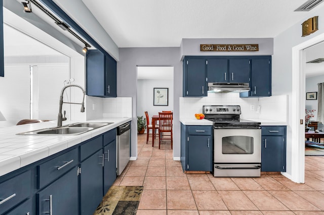 kitchen featuring appliances with stainless steel finishes, tasteful backsplash, sink, blue cabinetry, and light tile patterned floors