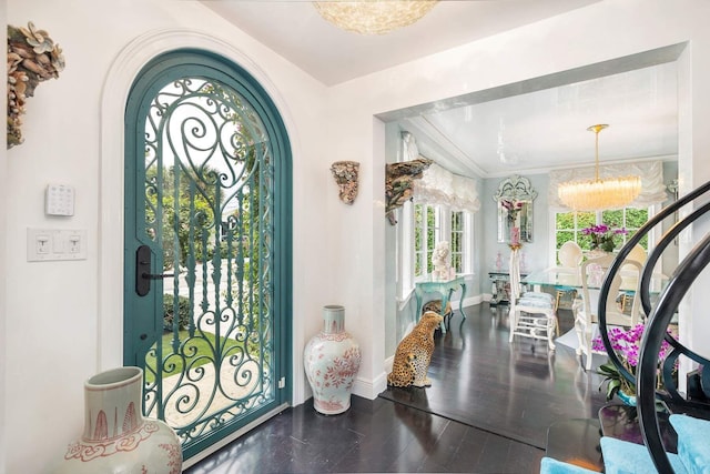 foyer entrance with hardwood / wood-style floors, ornamental molding, and a notable chandelier