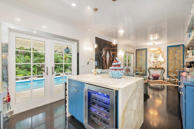 kitchen featuring light stone countertops, french doors, hanging light fixtures, beverage cooler, and a center island with sink