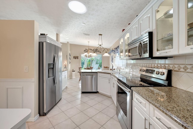 kitchen featuring light tile patterned floors, white cabinetry, stainless steel appliances, decorative light fixtures, and sink