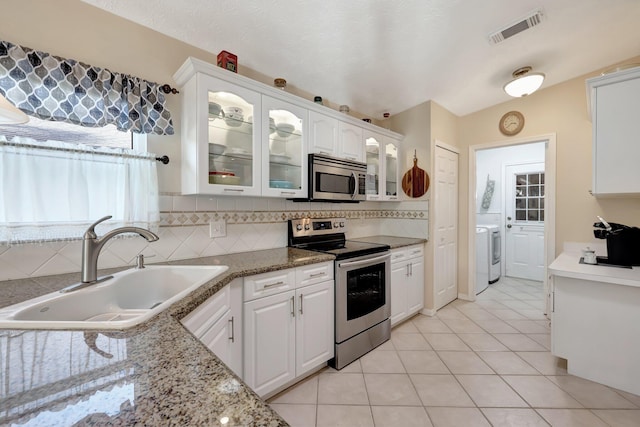 kitchen with light tile patterned floors, sink, stainless steel appliances, and white cabinetry