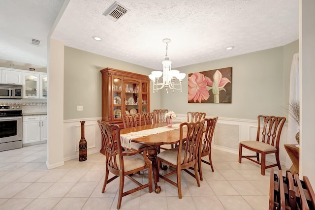 670 Senegal Ct, Fort Pierce, FL 34982 - dining area with a chandelier, light tile patterned floors, a wainscoted wall, a decorative wall, and recessed lighting