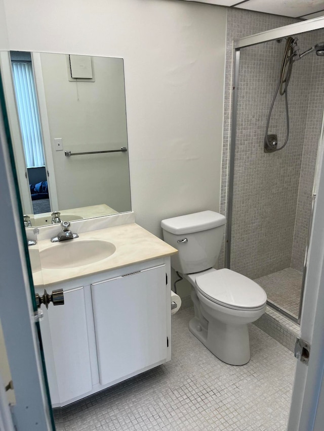 bathroom featuring toilet, vanity, tile patterned floors, and a shower with door